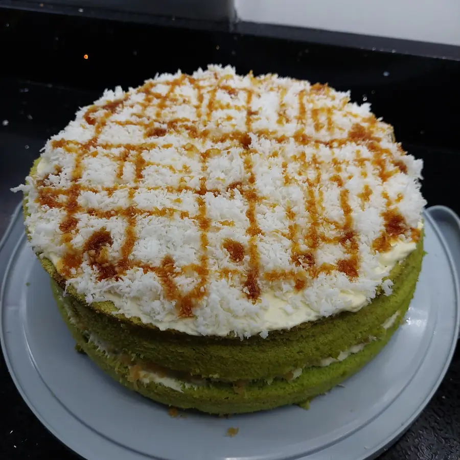 Green pandan layer cake topped with grated coconut and gula melaka drizzle